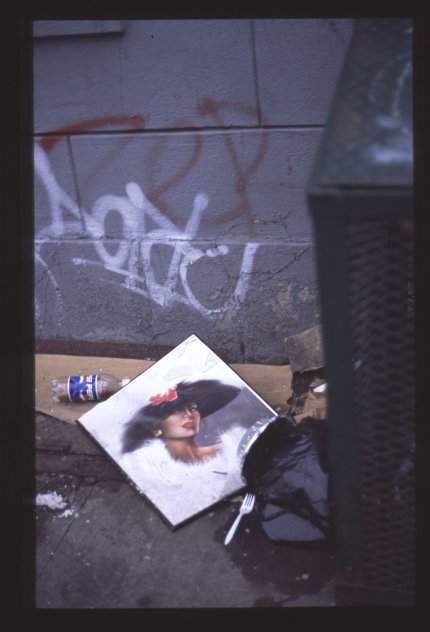 Naisen muotokuva maassa roskiksen vieressä